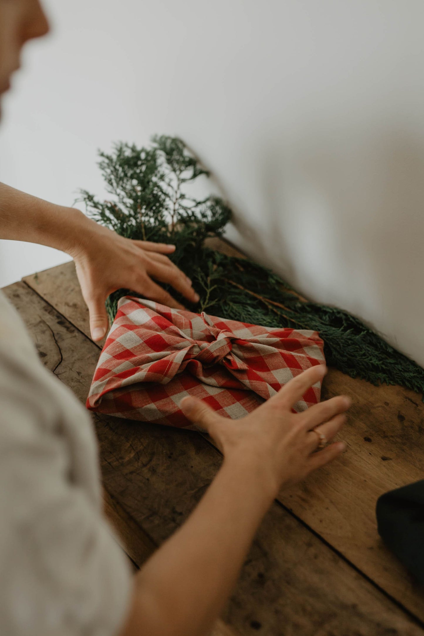 present being wrapped in gingham red furoshiki linen wrapping cloth