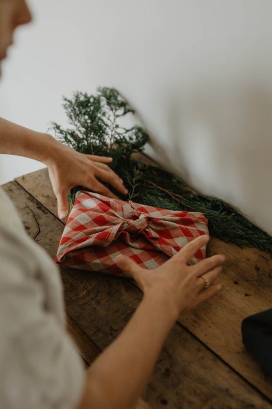 present being wrapped in gingham red furoshiki linen wrapping cloth
