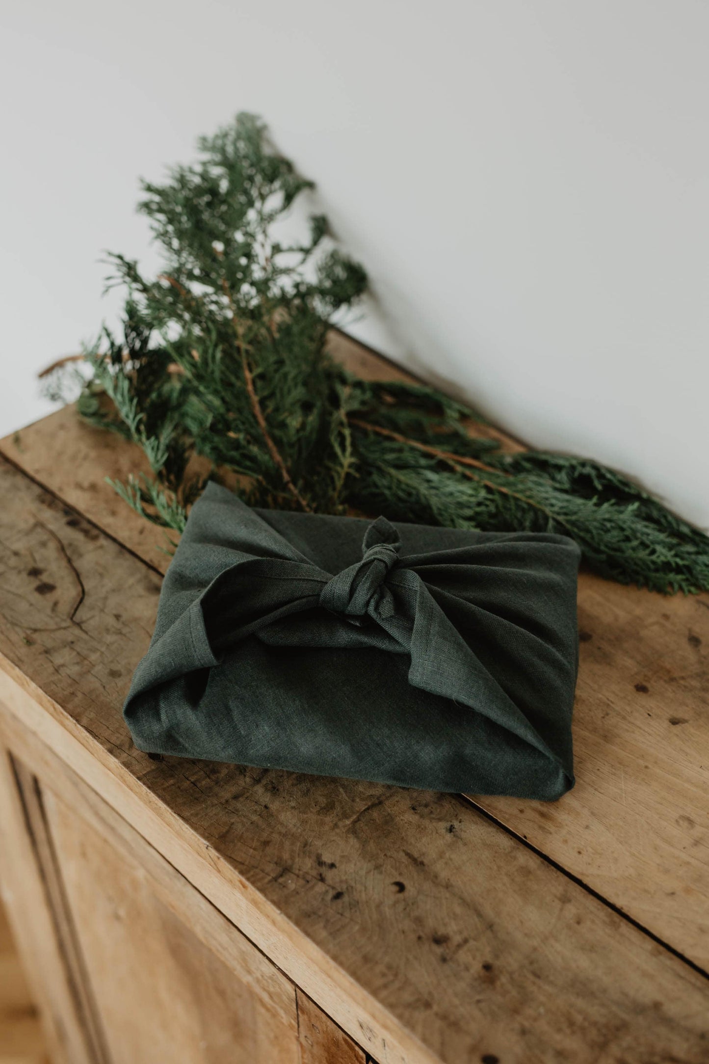 present wrapped in forest green linen furoshiki wrapping cloth