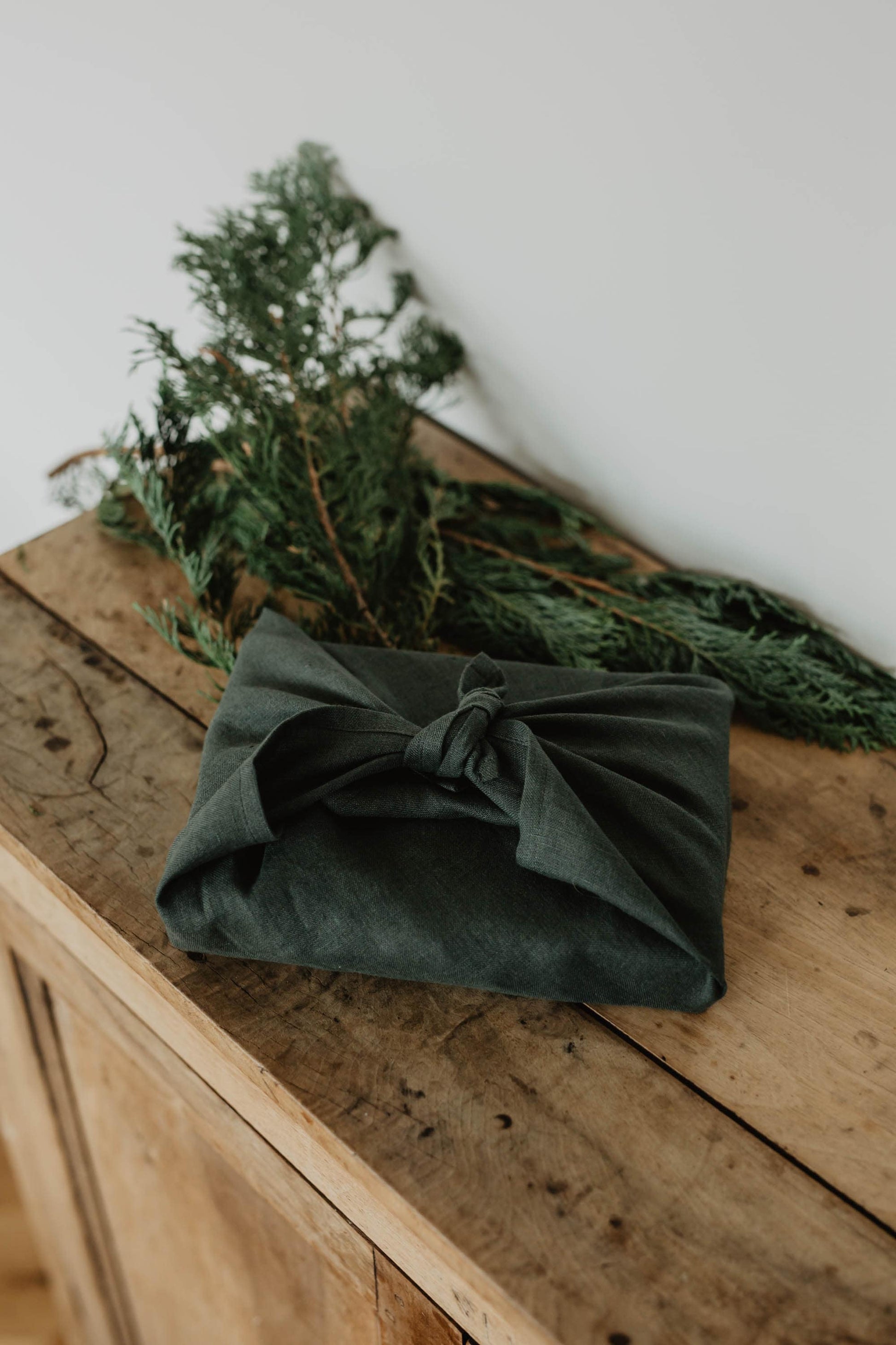present wrapped in forest green linen furoshiki wrapping cloth